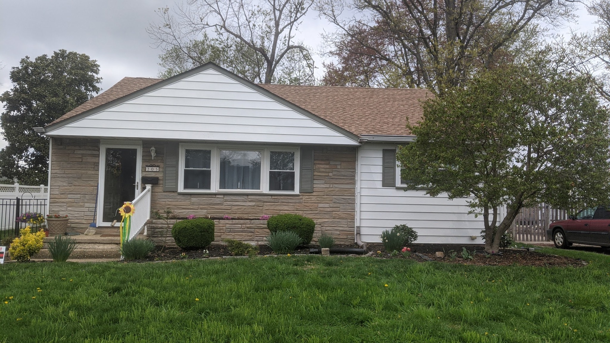 Front of the house in 2021. Bare mulch bed, two small shrubs, no plantings.